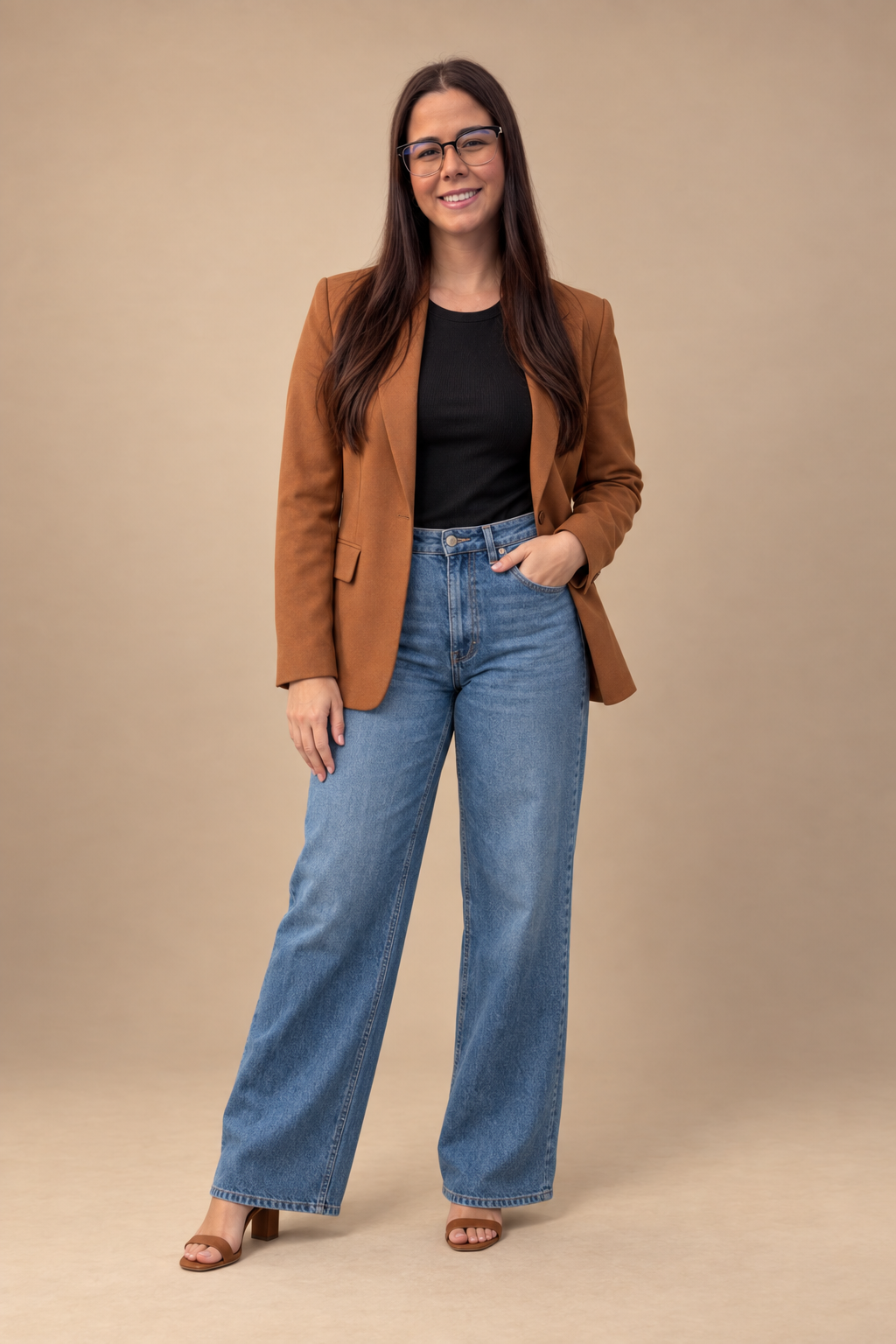 Débora Ribeiro em retrato de estúdio, com blazer caramelo e jeans